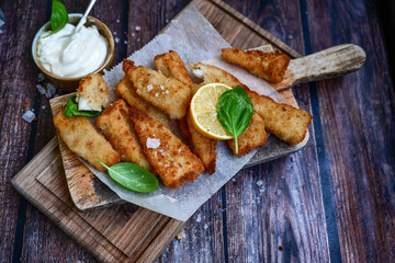   Allasca Pollock Fish  Bites in a crispy Tempura  Batter.Fish and chips .Close up of   crispy breaded  deep fried fish fingers with breadcrumbs s erved with remoulade sauce and  lemon