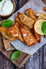   Allasca Pollock Fish  Bites in a crispy Tempura  Batter.Fish and chips .Close up of   crispy breaded  deep fried fish fingers with breadcrumbs s erved with remoulade sauce and  lemon