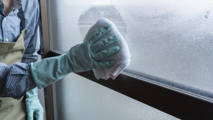 冬の窓の結露をタオルでふき取る