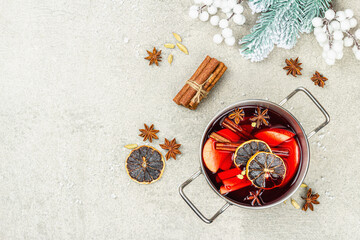 Mulled wine with spices in a pot with traditional Christmas decor. Hot beverage, festive background