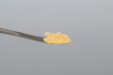 cannabis resin wax and dab tool for smoking close up on gray background