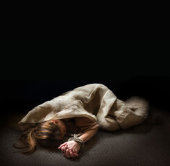 The bound prisoner lies on the floor