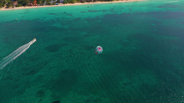 Aerial view of Parasailing, also known as parascending, paraskiing or parakiting. West Caribbean coast in Jamaica, Negril. Parachuting man in the air. parachute over the Seven Mile Beach.