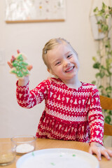 Smiling little girl showing off the Christmas cookie she just decorated