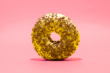 Yellow donut with chocolate crumbs on dark pink background. Creative food background