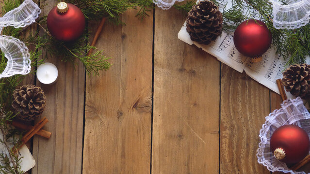 Christmas Flatlay of Pine Cones, Red Ornaments, Sheet Music, and Evergreen Boughs on a Wooden Background | Rustic Christmas Decorations
