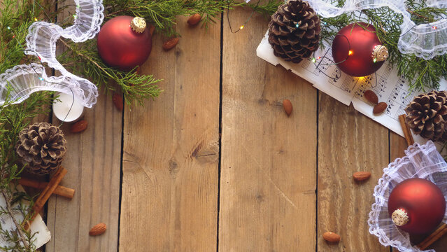 Christmas Flatlay of Pine Cones, Red Ornaments, Sheet Music, Christmas Lights and Evergreen Boughs on a Wooden Background | Rustic Christmas Decorations