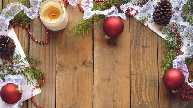 Christmas Flatlay of Pine Cones, Red Ornaments, Beads, Sheet Music, Candle, and Evergreen Boughs on a Wooden Background | Rustic Christmas Decorations