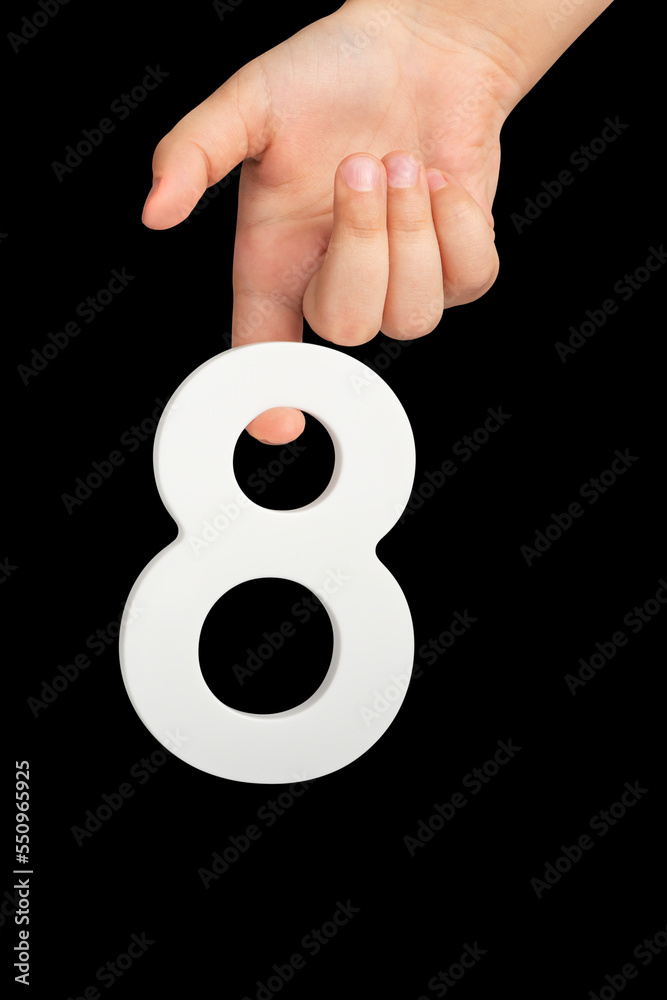 Poster number eight in hand isolated on black background. number 8 in a child's hand on a black background.
