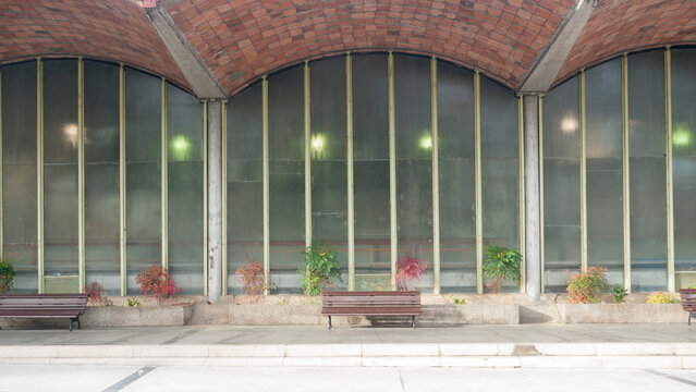 Bancos de madera junto a pabell&oacute;n de hormig&oacute;n verde y cristaleras