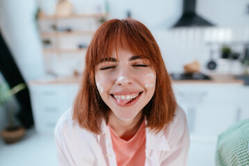 Playful young woman with flavor on face on the kitchen