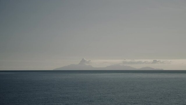 Scenic view of distant smoking volcano from ocean / Montserrat
