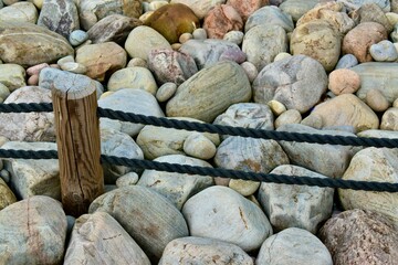 Fragment of a fence in Japanese garden of stones agains colourful rocks of various sizes background 