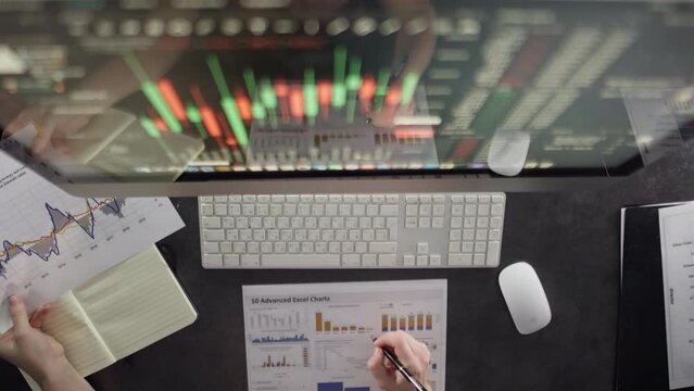 Close-up of businessman's hands going through documents with graphs at the workplace near the computer. The man works in the office on a PC. High quality 4k footage