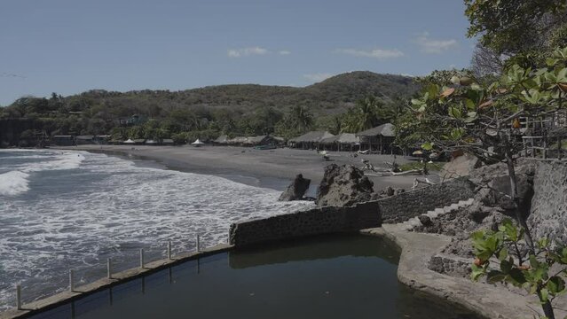 Scenic view of ocean waves on beach cove near swimming pool / Atami, La Libertad, El Salvador