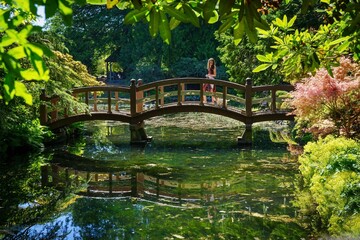 Woman crosses Japanese garden with bridge - Hatley Park, greater Victoria, Vancouver island, British Columbia, Canada 