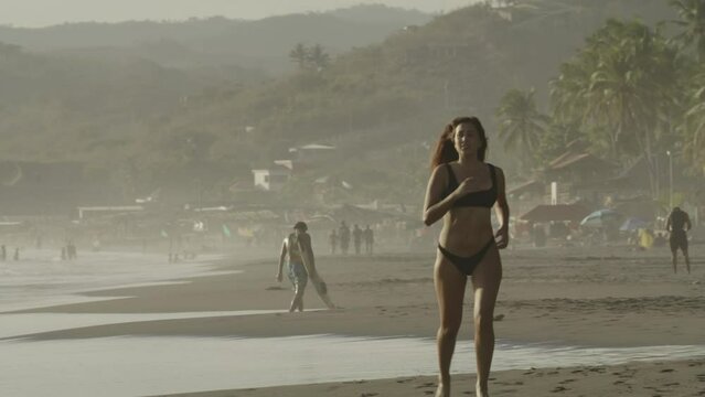 Approaching woman running on ocean beach / San Blas, La Libertad, El Salvador
