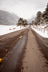 Looking down the middle of a snowy highway in Rocky Mountain National Park in the Winter, Estes Park, Colorado
