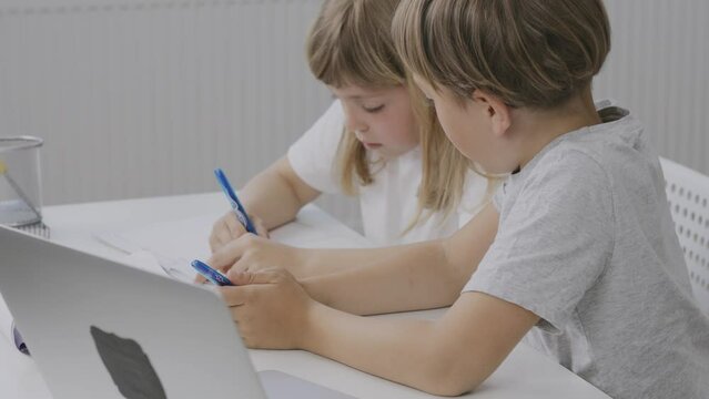 Brother helps his younger sister to make her homework.