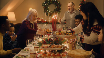 Happy large family sitting at table and celebrating Christmas or New Year at home. Grandmother set the table with traditional dish turkey. Warm atmosphere of family Christmas dinner. Christmas Eve.