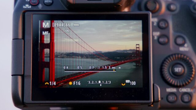 Beautiful sunset views over calm ocean waters of the Bay Area in San Francisco. Close-up view of professional camera taking photos of iconic Golden Gate Bridge. High quality 4k footage