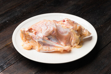 A fresh raw chicken rack against a dark background
