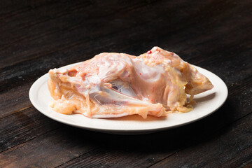 A fresh raw chicken rack against a dark background