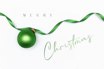Merry Christmas card. Green christmas ball on the green ribbon on the white background