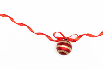 Elegant Christmas flatlay composition with red ball with golden stripes on the red ribbon with the bow