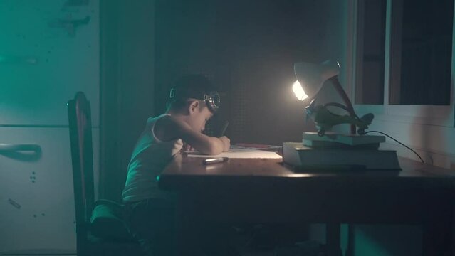 Child wearing googles  drawing and writing on a vintage kitchen table with artificial lighting and fog