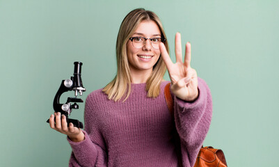 young pretty woman smiling and looking friendly, showing number three. science university student
