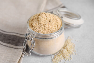 Sesame flour in glass jar on grey table