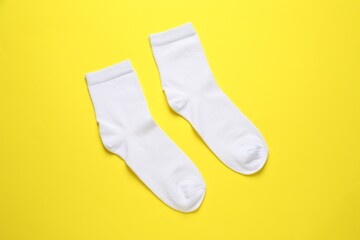 Pair of white socks on yellow background, flat lay