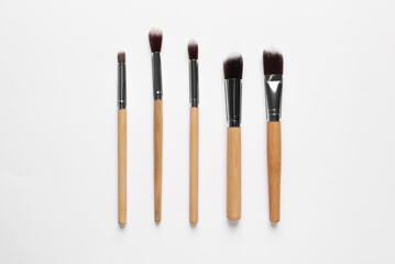 Different makeup brushes on white background, flat lay