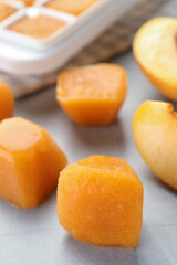 Frozen nectarine puree cubes and ingredient on light grey table, closeup