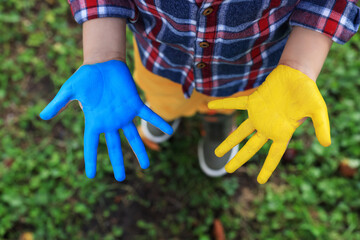 Little boy with hands painted in Ukrainian flag colors outdoors, top view. Love Ukraine concept