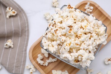 Bowl of tasty popcorn on white table, flat lay. Space for text