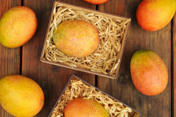 Delicious ripe juicy mangos on wooden table, flat lay