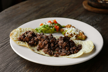 Plate with delicious tacos served on wooden table