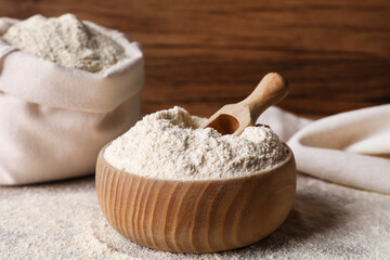 Wooden bowl with quinoa flour and scoop on table