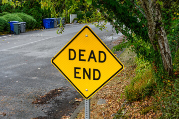 Yellow road sign in a residential, Dead End, garbage bins in background for garbage day

