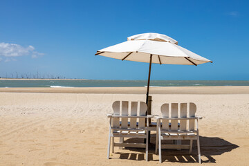 Wooden chairs and an umbrella on a tropical beach on a sunny day. Paradise on the beach.