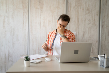 one man sitting at the office at work having eye strain pain eyestrain