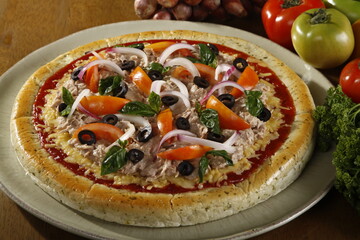 Fresh whole and unsliced tuna pizza with ingredients at the side