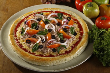 Fresh whole and unsliced tuna pizza with ingredients at the side