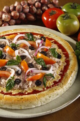 Fresh whole and unsliced tuna pizza with ingredients at the side