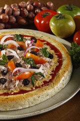 Fresh whole and unsliced tuna pizza with ingredients at the side