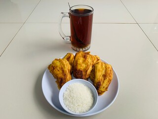 fried bananas with added sugar and accompanied by a glass of hot tea. very good when it rains