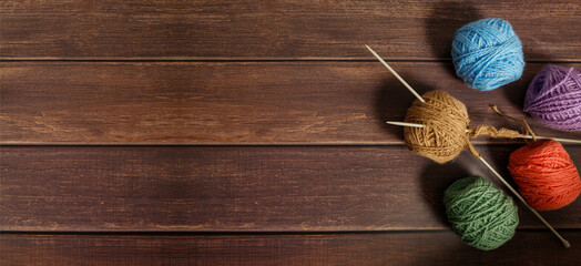 Knitting wool and knitting needles on dark wooden background. Top view handmade background. Copy...