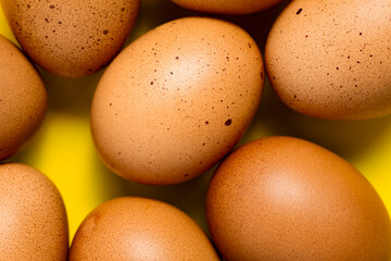Brown chicken eggs on yellow background. Fresh chicken eggs background. Top view with copy space